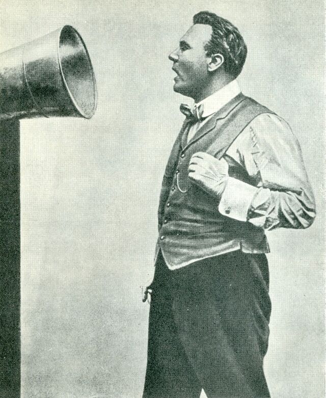 Dobová fotografie: operní pěvec zpívá do nahrávacího trychtýře, 1913